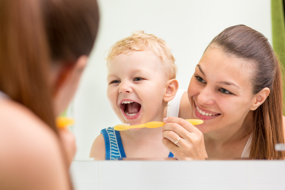 Parent helping child brush teeth